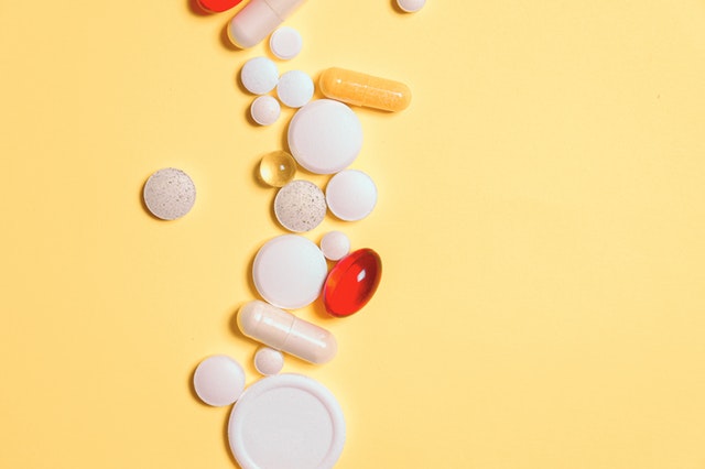 red-and-white-medication-pills-on-yellow-surface-3683049